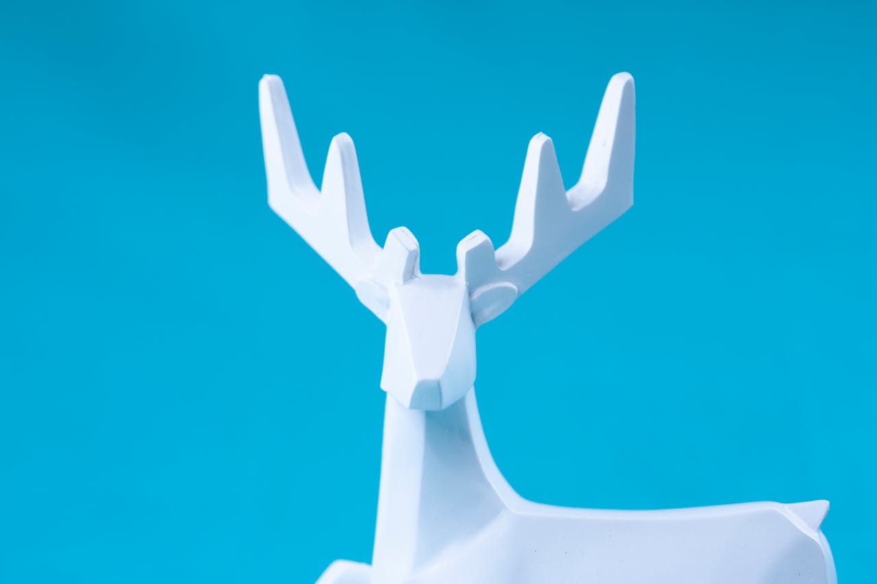 Head of minimalist style deer figurine with geometric antlers against vibrant blue background
